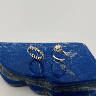 a pair of silver rings sitting on top of a blue stone