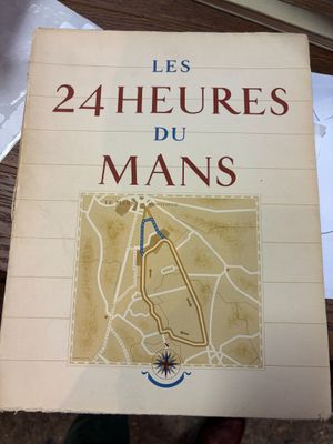 une personne tenant un livre sur lequel figure une carte, posé sur une table