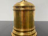 a gold plated container with a lid on a black table