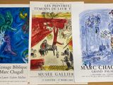 trois affiches représentant des tableaux, posées sur une table au plateau en bois