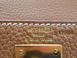 the brown leather bag has a brass plate on it