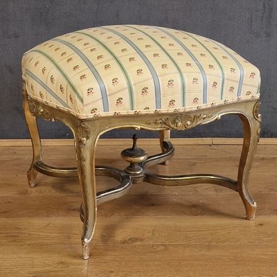 un petit tabouret avec une assise rayée, posé sur un plancher en bois