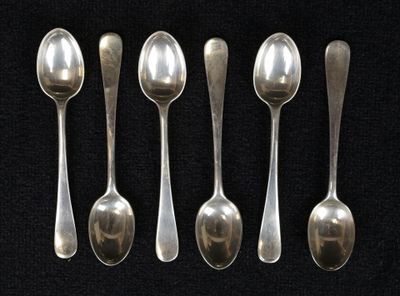 six cuillères en argent sont alignées sur une surface noire