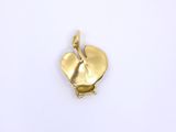 a close up of a gold leaf charm on a white surface