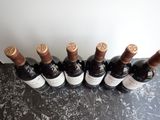 six bottles of wine are lined up on a table