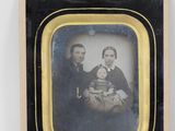 portrait of a man and woman holding a baby in a black and gold frame