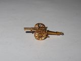 a small gold pin with a cannon on it