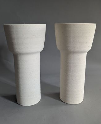 two white vases sitting next to each other on a table