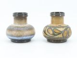 two vases sitting side by side on a white surface