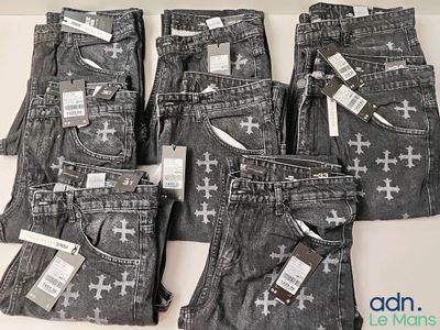 cinq paires de jeans ornées de croix, posées sur une table