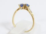 an image of a gold ring with two blue sapphires on top of a clear rock
