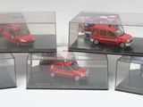 six petites voitures rouges dans des boîtes transparentes, posées sur une surface blanche