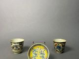 three cups and a saucer sitting on top of a table