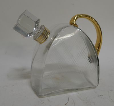 a clear glass bottle with a gold handle on a table