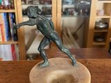 bronze statue of a man holding a tennis racquet on a wooden base