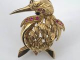 a close up of a gold bird brooch with pink stones