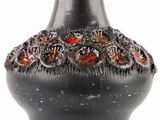 a black vase with red flowers on it on a white background