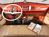 a small red car with a steering wheel and a book on the seat