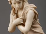 marble statue of a woman kneeling on a rock with her hands on her knees