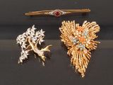 two gold and silver brooches and a pin on a black surface