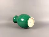 a green vase sitting on top of a white table