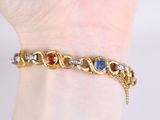 an image of a woman ' s hand holding a gold bracelet with multi colored stones