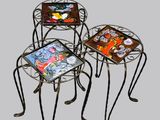 three metal tables with colorful tile designs on them on a gray background