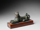 une statue en bronze représentant un chat, posée sur un socle en bois