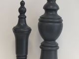 deux vases noirs posés sur une table blanche, avec une horloge en arrière-plan