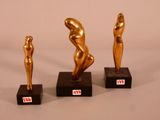trois sculptures en bronze représentant un homme et une femme, posées sur des socles noirs