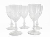 four clear wine glasses sitting next to each other on a white surface
