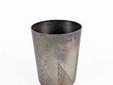 an old silver cup sitting on top of a white surface