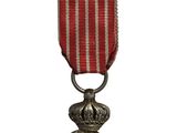 une vieille médaille ornée d'un ruban rouge et d'une médaille en argent