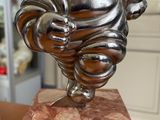 une statue représentant un homme tenant un poisson, posée sur un socle en marbre