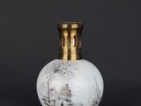 a white and gold vase sitting on top of a black table