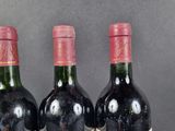 three bottles of red wine are lined up on a table