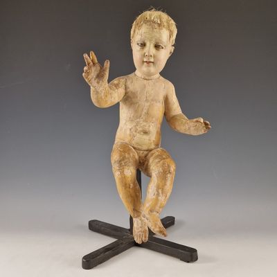 statue d'un bébé assis au sommet d'une croix en bois