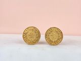 a pair of gold coin earrings sitting on top of a marble counter