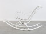 a white rocking chair in a room with a white wall