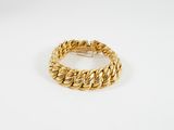 gros plan d'un bracelet en or sur une surface blanche