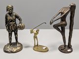 trois figurines en bronze représentant un homme avec un club de golf et un chien