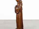 a wooden statue of a man in a monk ' s robes