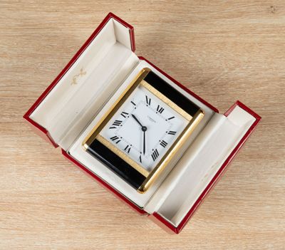a small clock in a red box on a wooden table