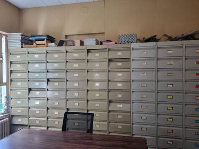 un bureau sur lequel est posé un ordinateur portable, devant un mur de classeurs