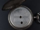 a silver pocket watch sitting on a black surface