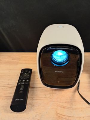 un petit projecteur posé sur une table en bois, avec une télécommande