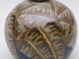 a brown and blue vase sitting on a white surface