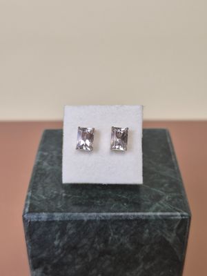 a pair of earrings sitting on top of a marble block