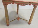 an old wooden table with a painted top on a white floor