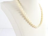pearl necklace on a mannequin head with a white background